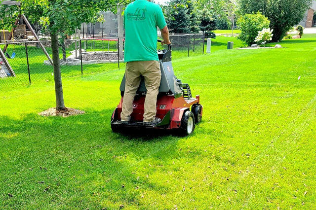 A Green4Ever Lawn Care specialist working a lawn aeration machine.